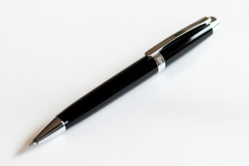Single black pen with a smooth barrel, lying horizontally on a clean white surface. 