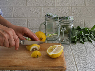 A woman slices lemon slices for a refreshing drink.