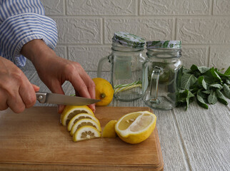 A woman slices lemon slices for a refreshing drink.