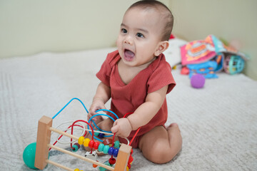 Happy baby with a colorful wooden toy maze, highlighting early childhood development and sensory...