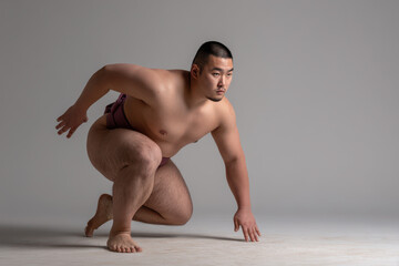 Obraz premium focused japanese sumo wrestler in dynamic warmup pose positioned on left side of frame