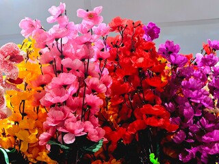 A vibrant bouquet of artificial flowers in shades of pink, red, orange, and purple, perfect for...