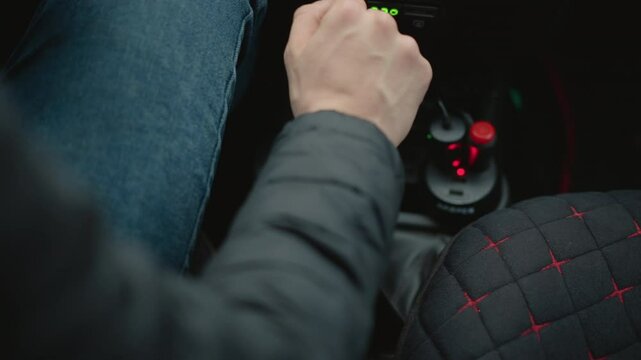 High angle view of car lover shifting gear lever forward with smooth practiced motion, wrist and knuckles guiding precise manual transmission engagement during urban drive on rainy streets