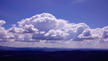 a breathtaking view of a sky filled with clouds over rolling hills beneath them.