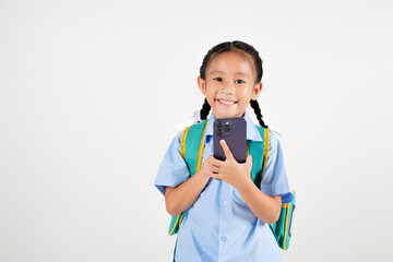 Portrait smiling Asian little girl kindergarten with backpack holding mobile phone studio isolated white background, happy woman kid in pigtails wearing school uniform use smartphone, back to school
