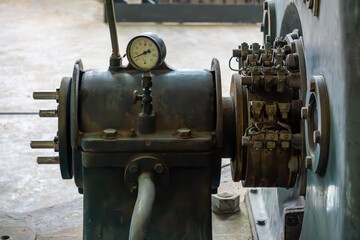 old industrial generator with a pressure gauge and exposed electrical connections. The machine is...
