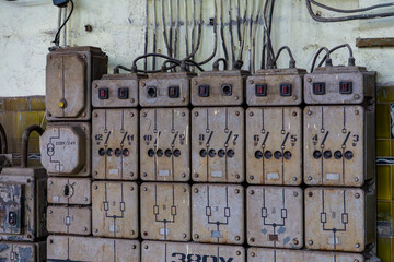 Old industrial electrical switchboard with multiple fuses and switches mounted on a wall. A gritty...
