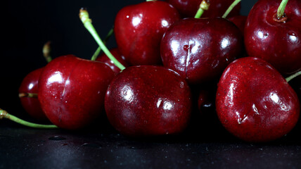 close up of group of red cherries on black background