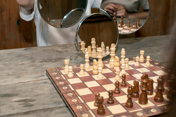 Chessboard with chess pieces reflected in a mirrors	