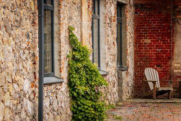 Weathered wooden chair and side table set against a red brick wall in a charming courtyard with...