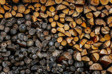 A close-up view of chopped and stacked firewood in various shades, textures, and sizes, showcasing...