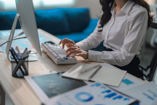 Businesswoman working on computer analyzing financial statistics displayed on the desktop screen, processing document for company strategy planning
