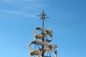 A metallic sculpture features a spiraling white garland and a star topper, set sharply against a...