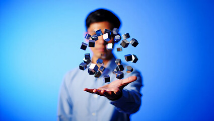 Man holding floating metallic cubes against blue background image