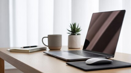 Fototapeta premium A clean, minimalist desk setup for remote work. Includes a modern laptop, wireless mouse, coffee mug, small plant, and a notebook with pen. The background is bright and neutral (white or light grey), 