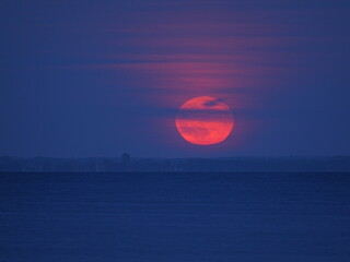 Strawberry Moon rises with a light veil, red and large, over the Greifswalder Bodden on the evening...