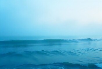 Calm blue ocean waves under a hazy blue sky