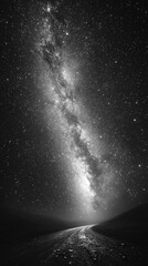 Starry night sky showcases a distant galaxy above a winding road, surrounded by a dark landscape, evoking feelings of adventure and cosmic beauty
