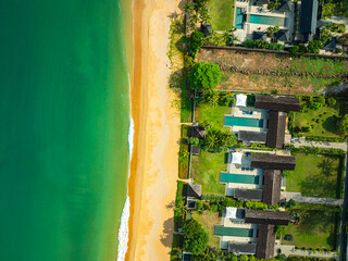 A stunning aerial view of a tropical coastline featuring golden sandy beaches, lush green pine trees, and turquoise ocean waves crashing against the shore. perfect for travel and nature visuals.