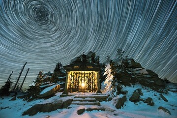 Chapel under Hochstein dedicated to Bishop St. Jan Neumann in the Šumava National Park near Třístoličník with star trails in winter. Photographed at night with snow