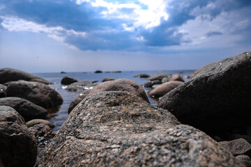 A tranquil seaside landscape characterized by rocks alongside a dramatic and colorful sky