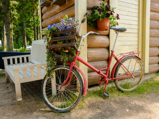 A Charming Red Bicycle Adorned with Bright Colorful Flowers Set Against a Cozy Log Cabin Background