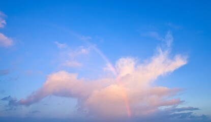 Sky Replacement with a part rainbow in front of a storm cloud on a blue sky.