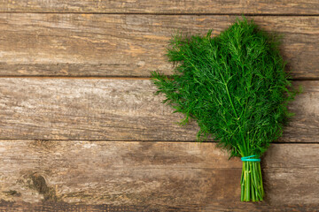 Dill on wooden background. Fresh organic greens. Dill plantation. Cut dill leaves. Bunch of spring young dill. Vitamins. Fiber. Aromatic culinary spice. Place for text. Copy space