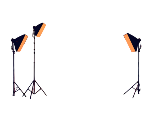 Isolated view of three stage lights with orange reflectors on stands in a dark environment