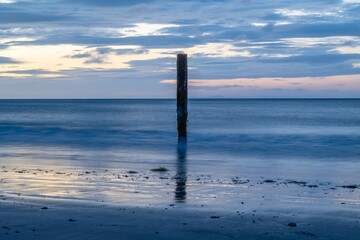 old wooden post in the sea at Swanage Dorset England at sunrise with the sea blurred in the...