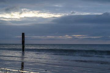 old wooden post in the sea at Swanage Dorset England at sunrise with the sea blurred in the...