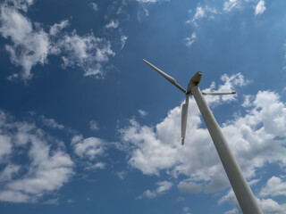 Damaged wind turbine against a bright blue sky with scattered clouds. Concept of renewable energy...