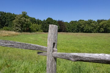 beautiful countryside scene featuring green fields, trees, blue sky, and a rustic wooden fence: