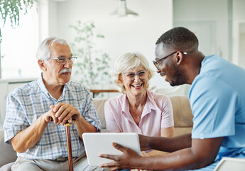 Doctor or nurse caregiver with senior couple using tablet at home or nursing home