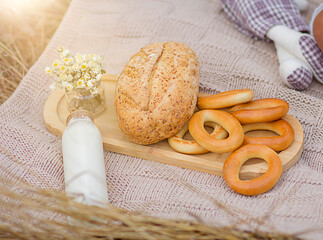a blanket with milk, bread, flowers, pastries, and a toy on a picnic. Postcard and painting