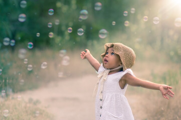 baby and soap bubbles. film photography. A little girl is waving her arms and trying to catch a lot of soap bubbles