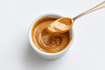 Smooth peanut sauce on spoon above white ceramic cup
