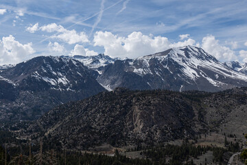Jagged granite range streaked with late-season snow rises beneath a vivid blue sky criss-crossed by...