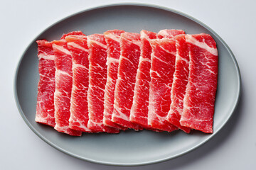 Thin slices of beef for shabu neatly arranged on gray plate
