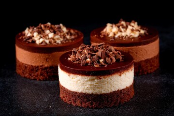 Three exquisite desserts feature layers of chocolate and cream, topped with chocolate shavings and nuts, showcasing a refined treat ideal for any special occasion