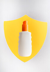 Sunblock or sunscreen in cosmetic tube against a shield as a symbol of sun protection. Summer vacation and skin care concept, spf uv-protect cosmetics. Skin health.