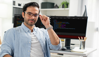 Profile's smart IT developer looking camera to pose wearing glasses against on software development...