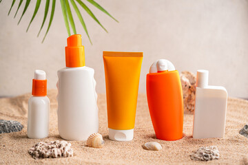 Sunblock or sunscreen in cosmetic tubes and bottles on beach sand and beige background. Summer vacation and skin care concept with starfish and sea shells, spf uv-protect cosmetics. Skin health.