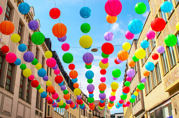 colorful paper lanterns hanging above street between buildings in city festive summer decoration