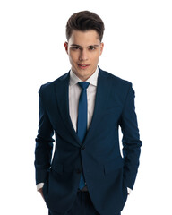 happy young man in navy blue suit with tie holding hands in pockets
