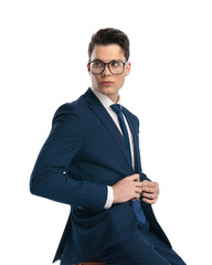 sexy young businessman with glasses buttoning navy blue suit