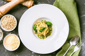 Italian cuisine. Fituccini al pesto on a white plate with a green napkin and cutlery with basil,...
