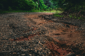 a gravel path or road with a washout channel and erosion from heavy rainfall. transportation or weather design element