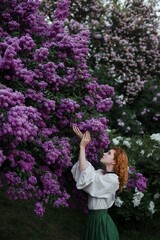 Young pretty caucasian woman in romantic outfit walking in blooming spring garden. Artistic outdoor photo of beautiful red-haired girl posing in fragrant lilac blossom.