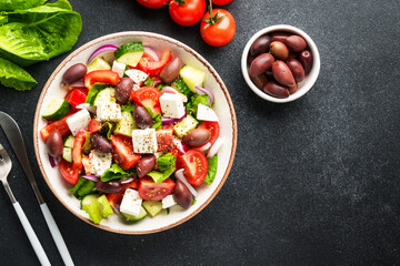 Greek salad in craft plate on black kitchen table. Top view. Vegan food.